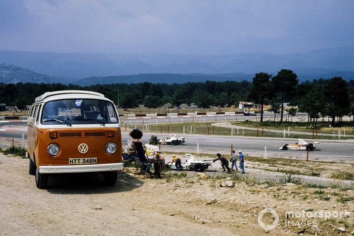 James Hunt, Hesketh 308B Ford lidera a Emerson Fittipaldi, McLaren M23 Ford en la pista mientras Jacques Laffite observa a los mariscales empujar su Ford Williams FW01 retirado a la zona segura