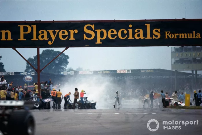 Trabajos de limpieza después del accidente en la primera vuelta. Graham Hill sale de su Shadow DN1 Ford a la derecha