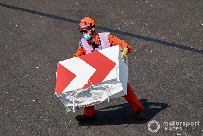 Los oficiales de pista reparan la barrera rota después de que Sebastian Vettel, el Ferrari SF1000 chocó con ella