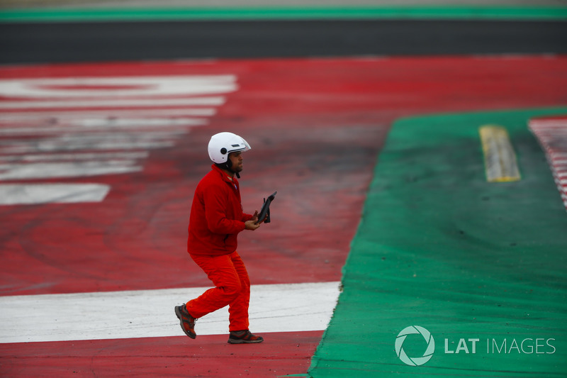 Un mariscal recoge un pedazo de escombros de la pista