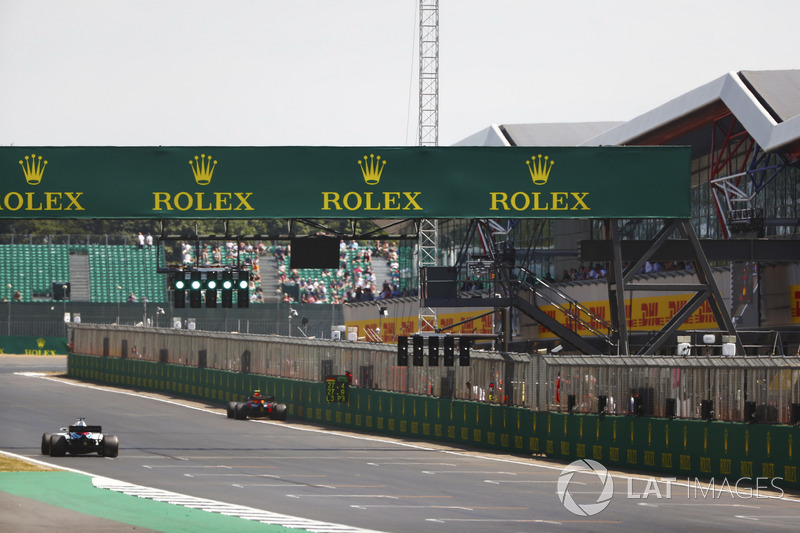 Max Verstappen Red Bull Racing RB14 is parked next to the pit wall, as Lance Stroll, Williams FW41, passes