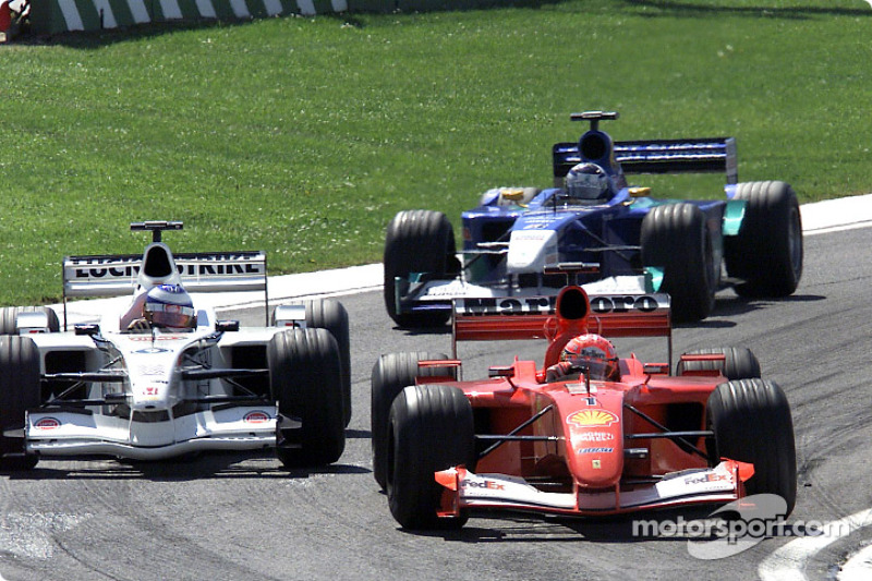 Michael Schumacher passing Olivier Panis, with Kimi Raikkonen watching