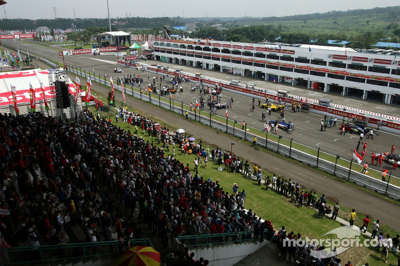 The crowd watch the cars on the grid before the start of the race