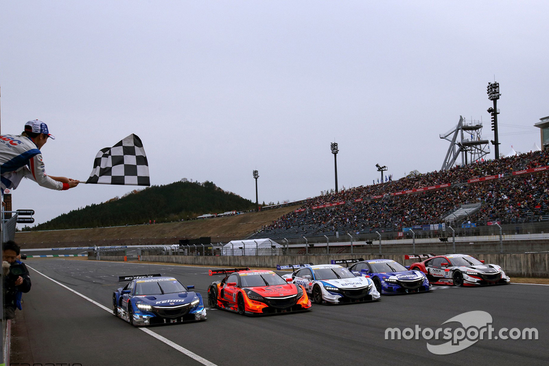 Takuma Sato waves the checkered flag over the Super GT Honda entries